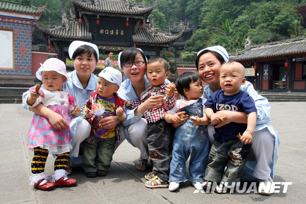 5月11日，三名护士王丽（左二）、罗云莉（左四）和张兰（右二）在曾经护理过“地震宝宝”的广场上与5名婴儿合影。